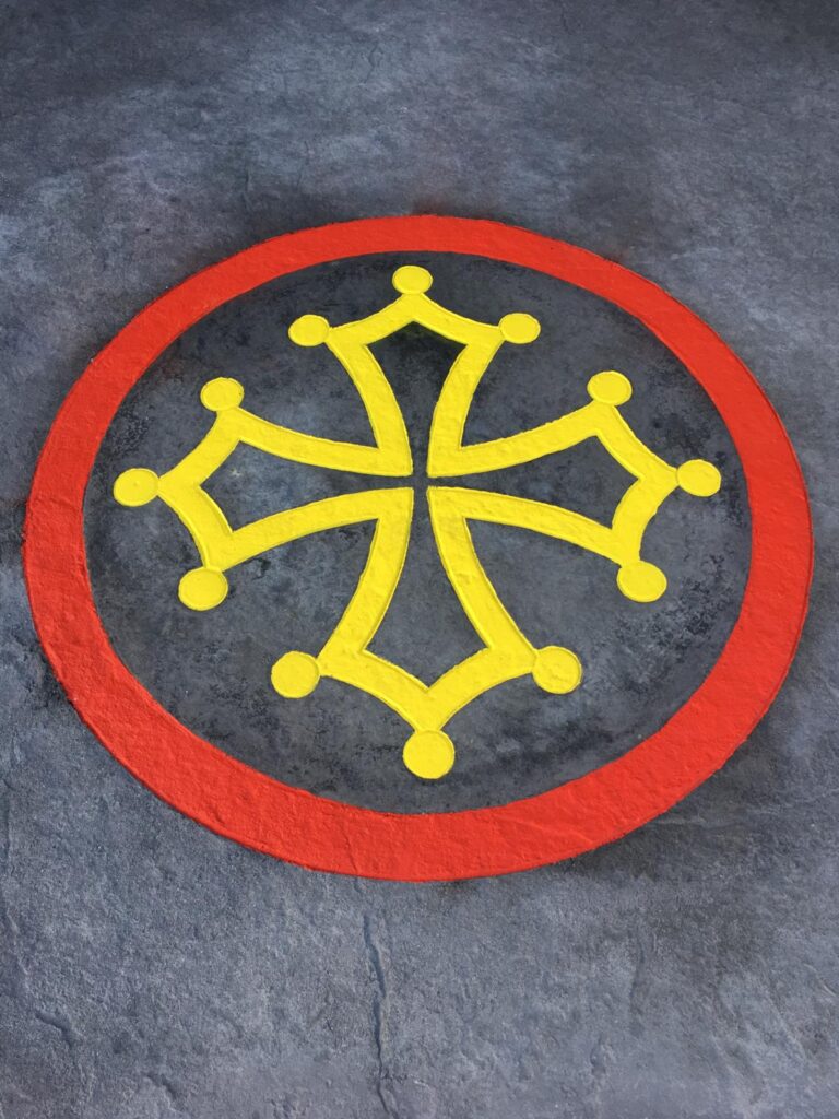 Croix Occitane Jaune et Rouge : Symbole sur Sol de Pierre Croix occitane jaune à douze pommettes dans un cercle rouge peinte sur un sol gris texturé.